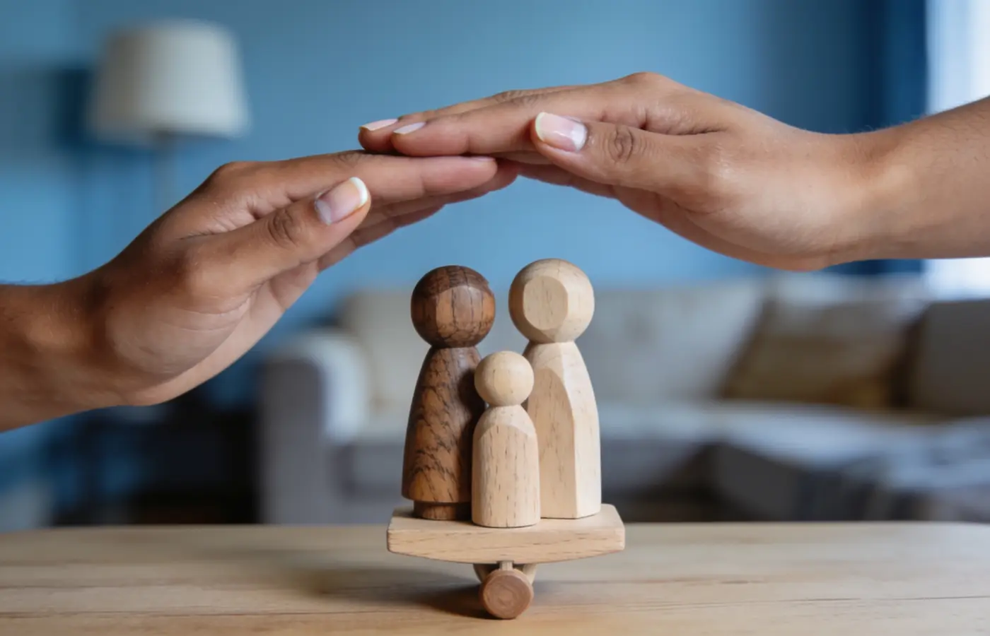 Mains protégeant une famille de figurines en bois